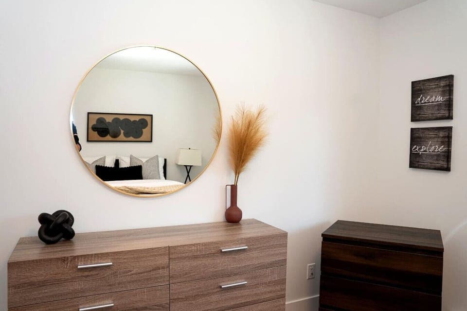 Primary bedroom with a queen bed, dresser, closet and blackout blinds.