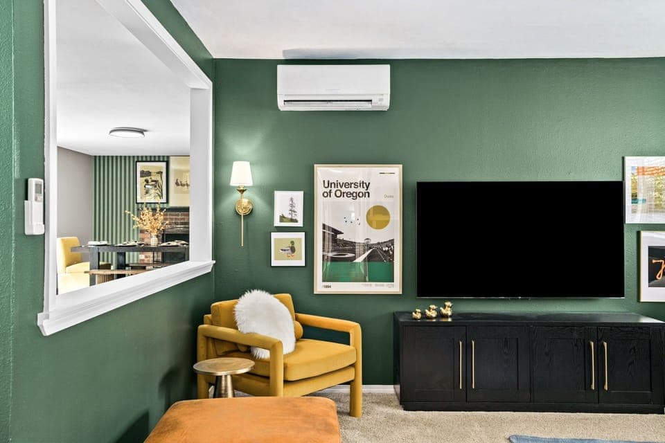 Inviting living room with sectional sofa, ottoman, chairs, and 65" smart TV. 