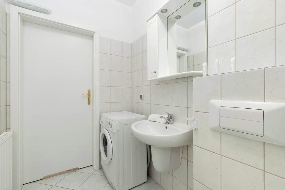 A bathroom with a comfortable shower, light ceramic tiles, and a large mirror above the sink creates a comfortable and functional space for daily care.
