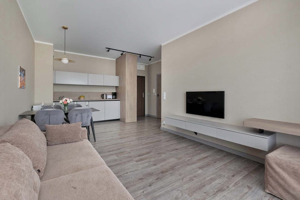 A spacious living room with modern decor, a comfortable corner sofa, and a large wall-mounted TV invites shared moments of relaxation.