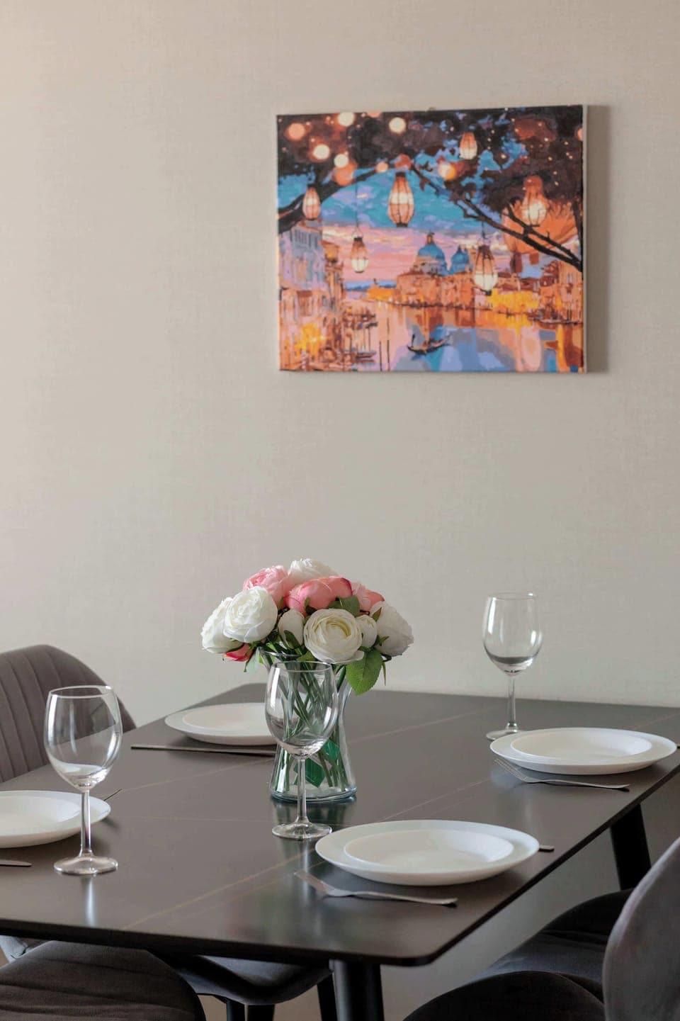A dining table decorated with fresh flowers and a softly colored painting hanging on the wall in the background add subtle charm to the interior.