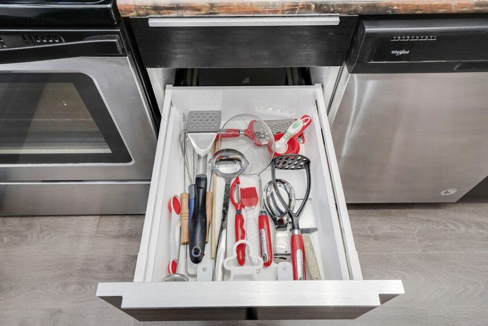 Fully stocked kitchen drawer with essential cooking utensils including whisks, spatulas, can opener, and more. Conveniently located beside the oven & dishwasher for easy access. Everything you need for preparing meals is readily available!