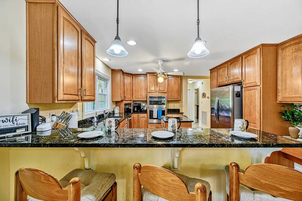 Kitchen - Breakfast bar with four stools, pendant lights, and granite countertops ready for casual meals.