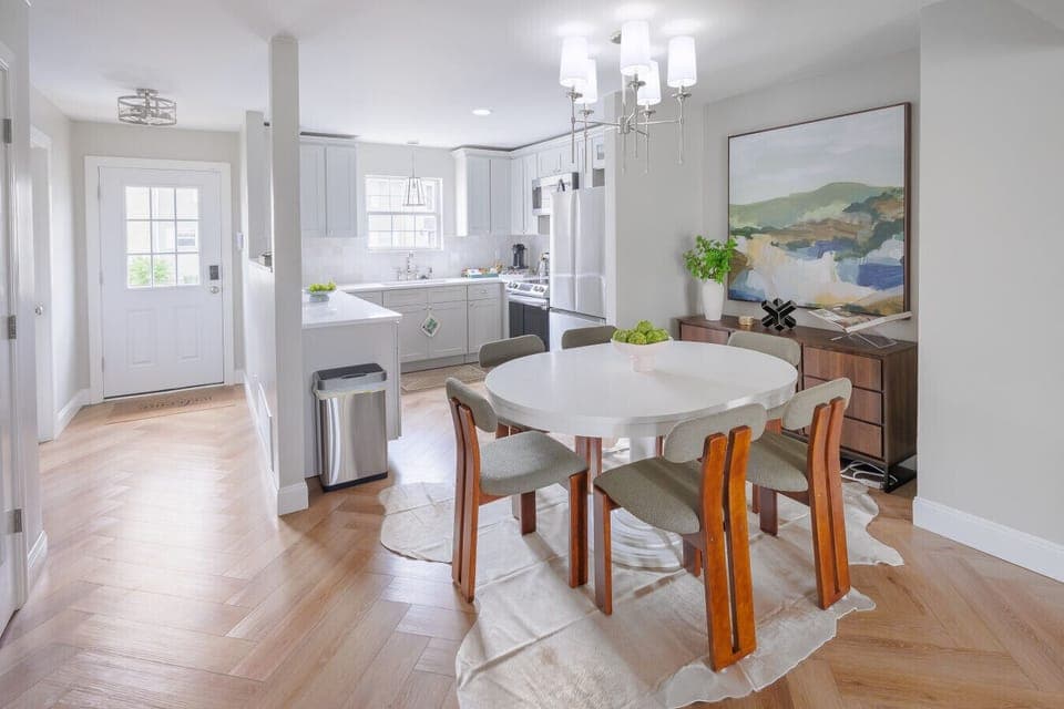 Dining table + bar seating accommodates all 12 guests for meals together. Modern light fixture, cowhide rug, designer chairs.