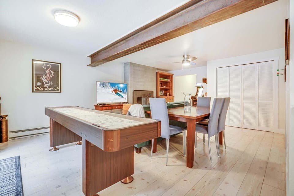 Dedicated game space with darts, arcade, shuffleboard, game console, Movie Library, and full kitchen with dining table.