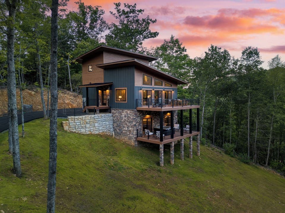 Two-story cabin with deck and forest backdrop