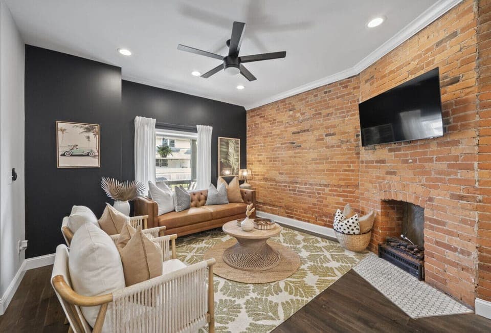 Relax in the cozy living room with exposed brick walls and stylish decor   - Comfortable seating and smart TV create the perfect gathering spot   - Natural light fills this inviting modern space