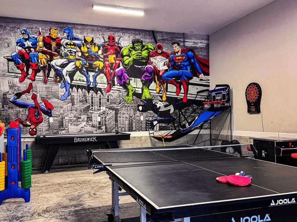 Epic climate-controlled game room featuring a massive 20’ x 10’ superhero mural—where every night feels legendary. Enjoy air hockey, ping pong, darts, arcade games, basketball, and more. 