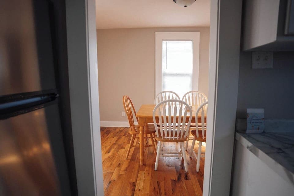 The dining area has a solid wooden table with six chairs, great for meals or hanging out. 