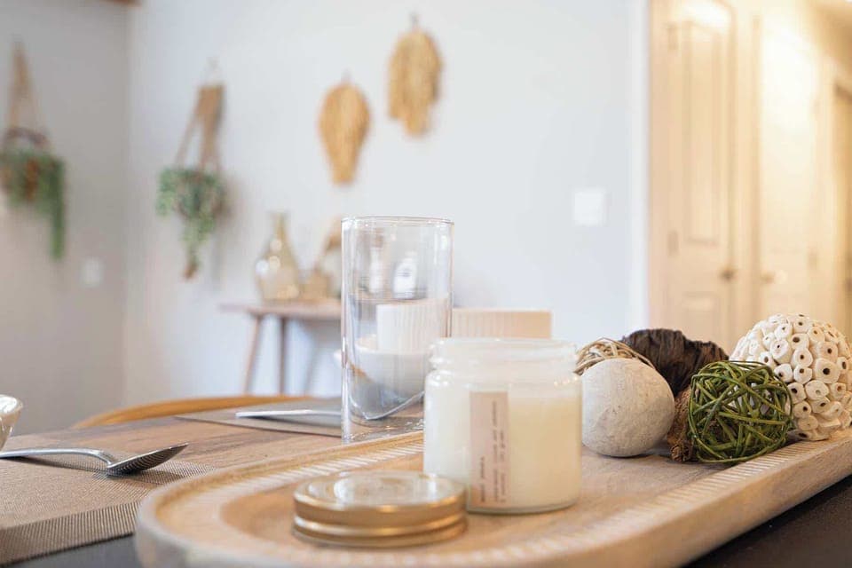 Natural centerpiece arrangement​ combining candlelight, glass vessels, and yarn balls that complement nearby hanging decorations.