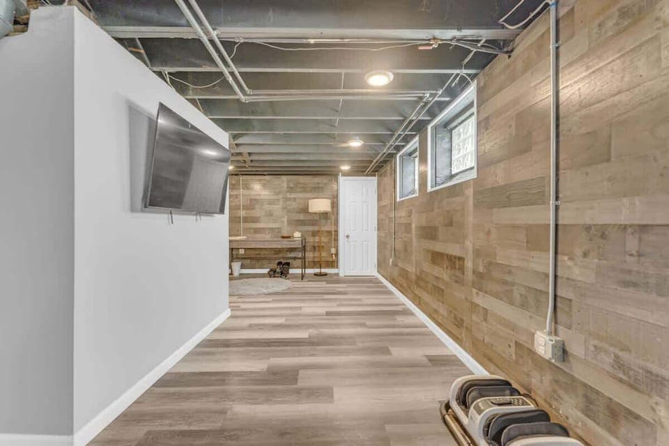 - Basement with fitness equipment and open space   - Mounted TV and seating for entertainment nights   - Wide layout perfect for exercise or relaxation  