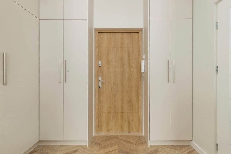 Tall white wardrobes with a wooden accent offer plenty of storage space and keep everything neatly organized.