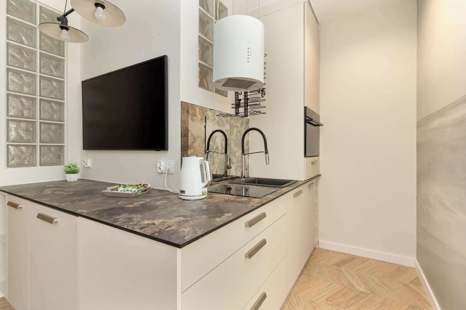 A modern kitchen with a black countertop and white cabinetry offers a convenient space for cooking and storage.