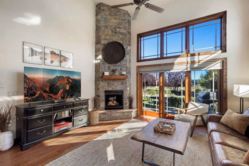 Open living room with cathedral ceilings, fireplace, smart TV and access to outdoor patio.
