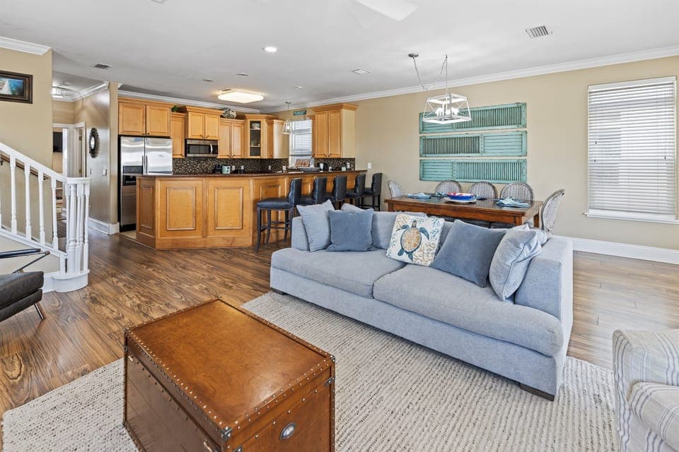 Relax in your spacious open-plan living area where coastal blue sofas invite evening conversations while the full kitchen awaits your culinary adventures.