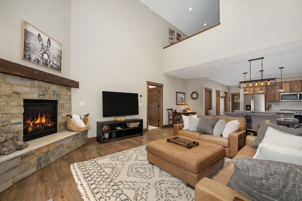 Unwind by your crackling stone fireplace in this open-concept living space, where leather seating and modern amenities create the perfect mountain retreat.