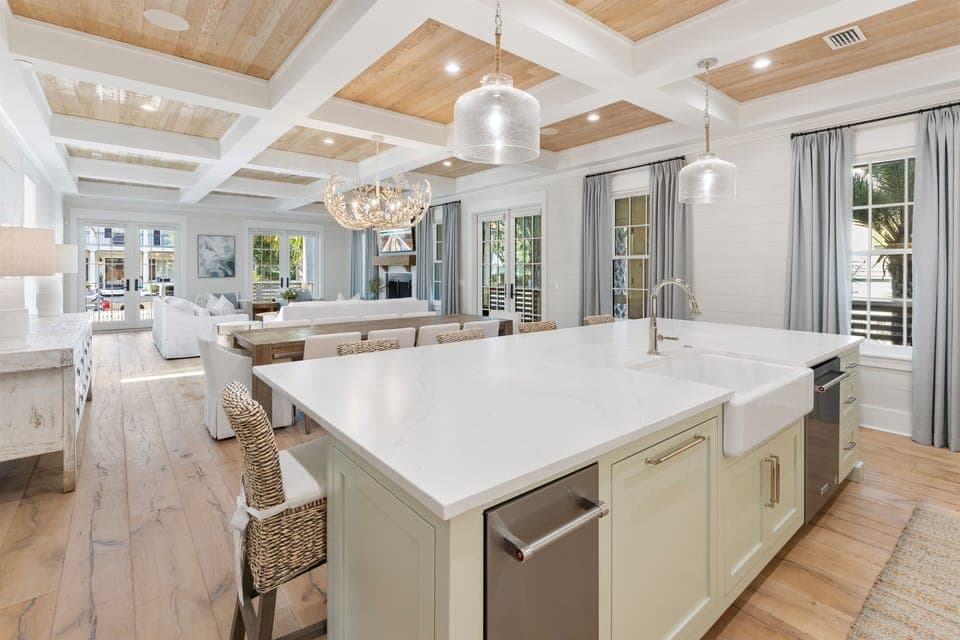 Your gourmet kitchen flows seamlessly into the living space, where natural light pours through elegant windows and coffered ceilings create warmth above.