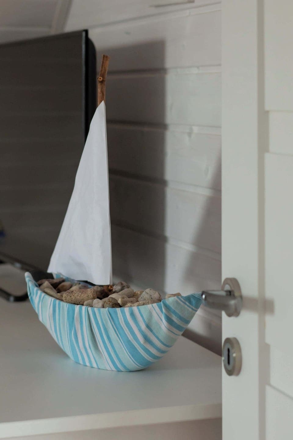A close-up view of a mini-boat standing on a shelf.