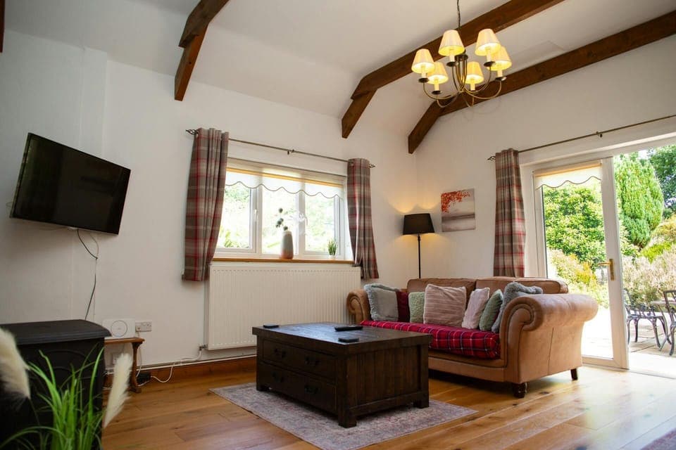 Lounge with 2 seater sofa, wall mounted TV and doors leading to the patio