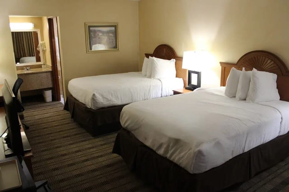 Unwind in a spacious double-queen room with warm lighting.