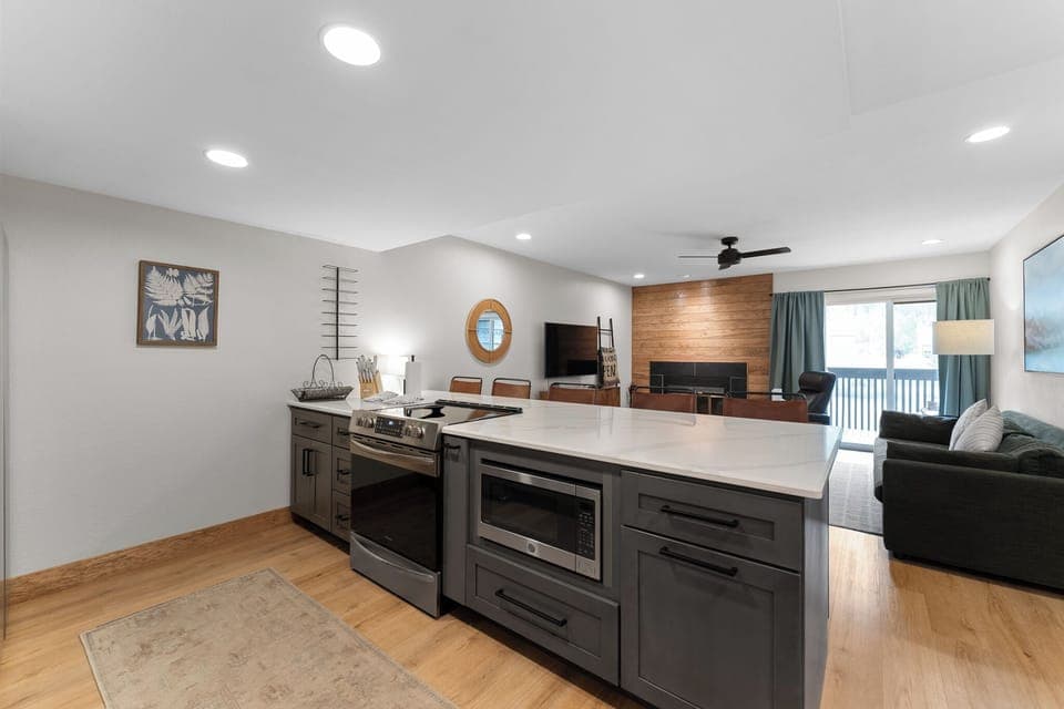 The modern kitchen features stainless steel appliances, and breakfast bar seating.