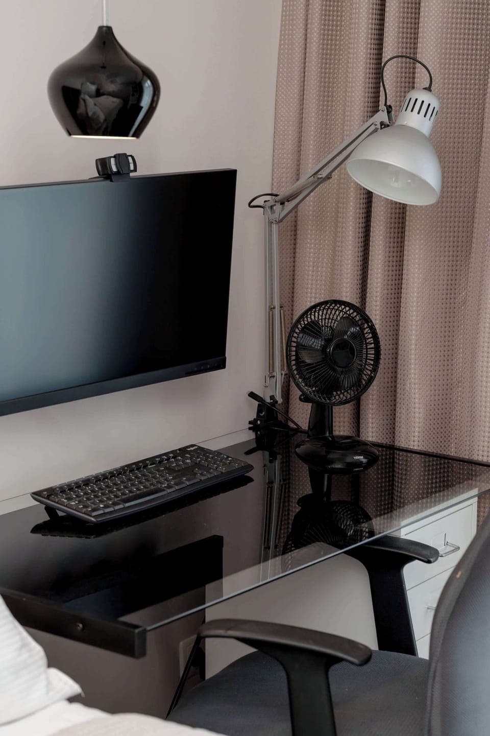 A working corner with a small black desk, TV above, and modern lamp. Functional space for productivity.