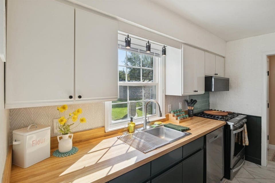 Sunlight warms the counter in our South Bend kitchen, where new stainless Whirlpool smart appliances, spices, utensils, and flour are stocked for alfresco pizza nights near Notre Dame.