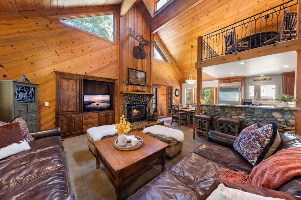 Vaulted great room with soaring wood ceilings, oversized seating, and stone fireplace — the heart of this Northstar ski retreat.