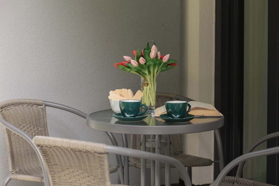 An outdoor seating area with a table and chairs. Surrounded by greenery, ideal for morning coffee.