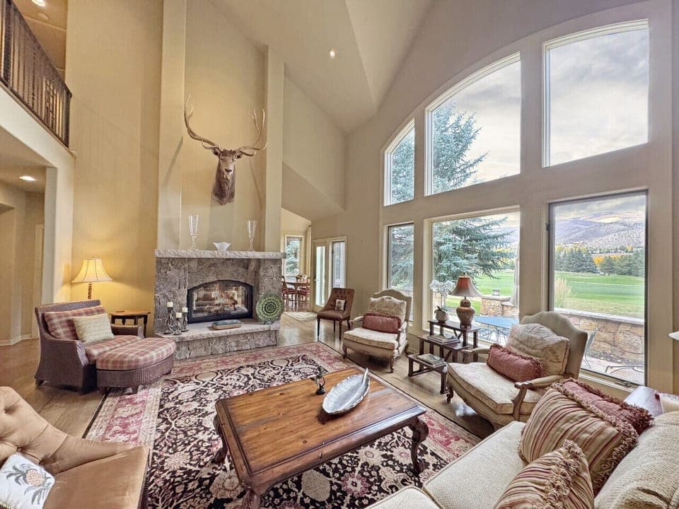 The great room with ample seating, a warm fireplace and a view of the valley and golf course