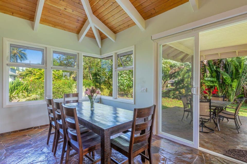 Enjoy meals together at Pohaku Villa’s dining table, surrounded by windows overlooking the lush gardens.