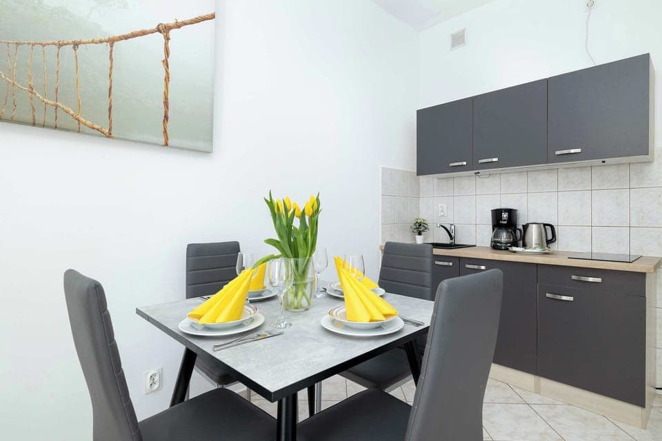 Stylish dining space set for four, featuring elegant dark chairs, a sleek table, and a vase of fresh yellow tulips adding a cheerful touch.