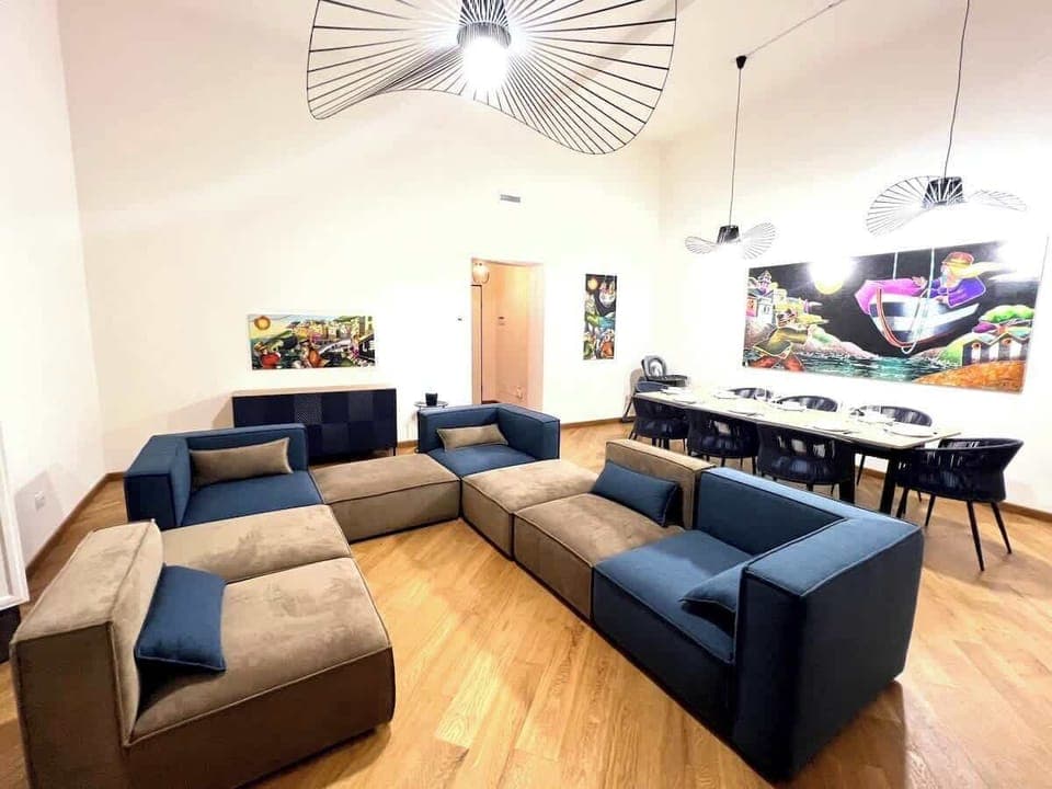 Vista del salone con in primo piano il divano modulare e tavolo da pranzo sullo sfondo.