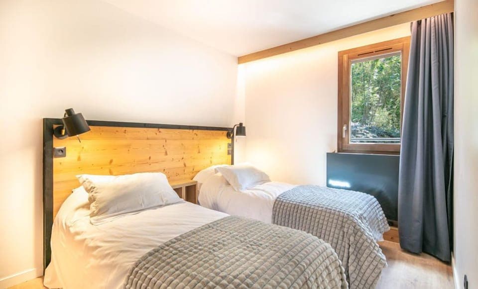 Natural light floods the second bedroom, highlighting the comfortable twin beds and tranquil decor.