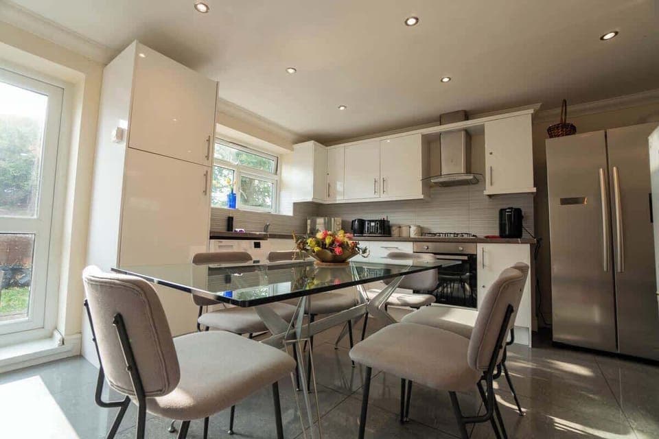 A large glass dining table surrounded by six plush chairs.
Natural light streaming in through a large window.