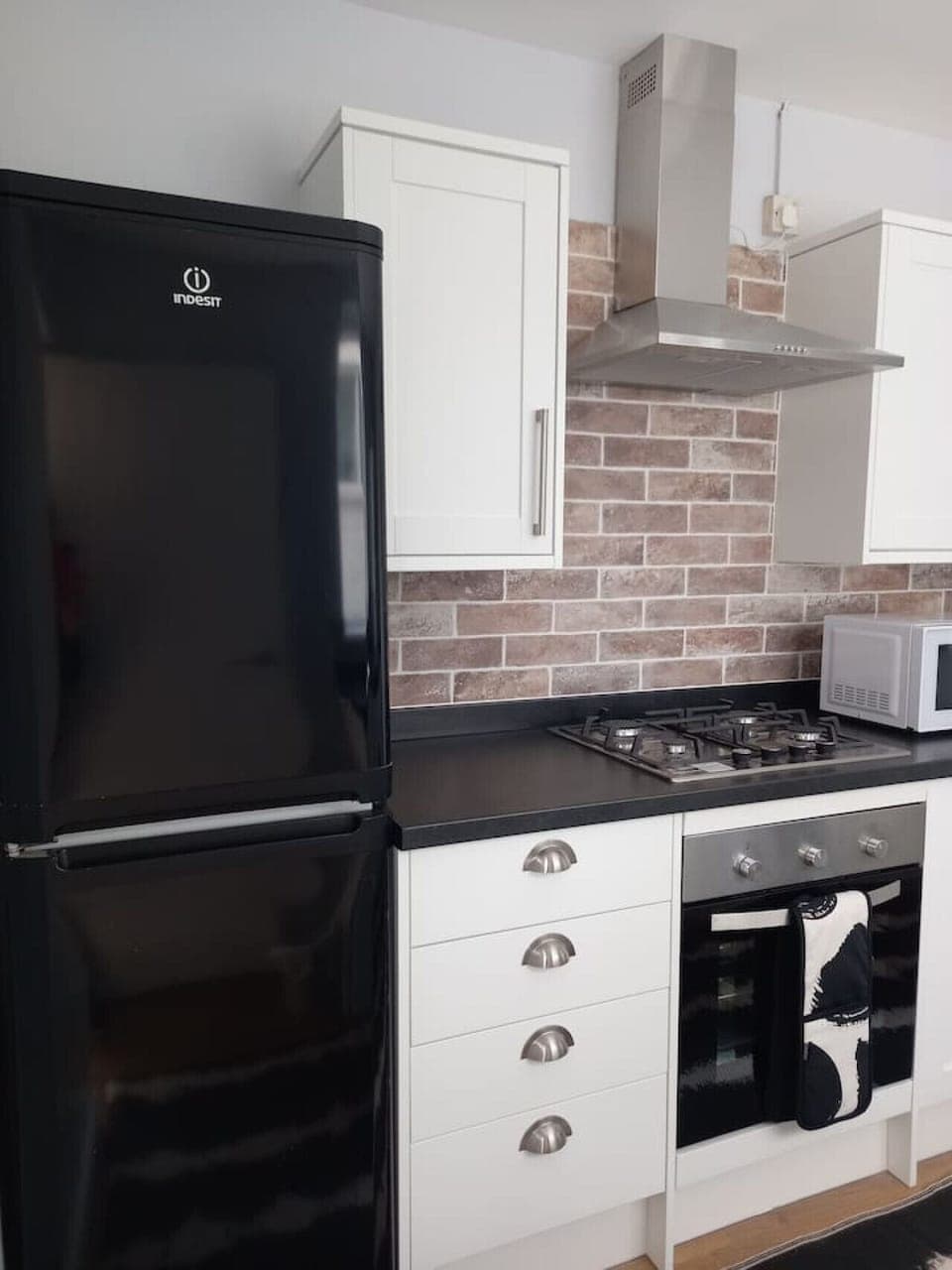 Modern kitchen with oven, hob, and black fridge freezer