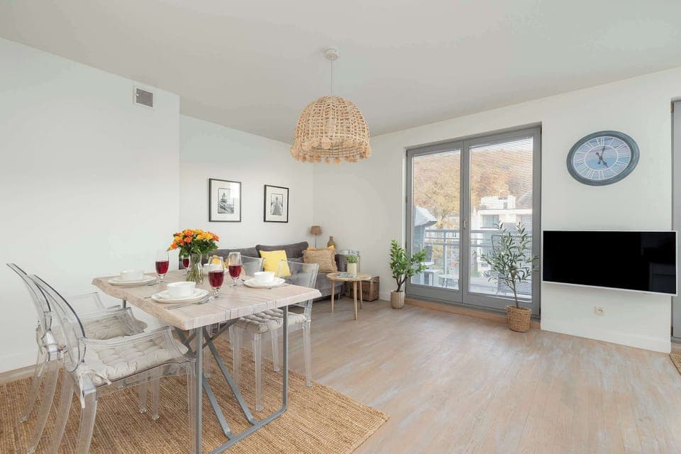 An elegant dining room with a simple table, natural lighting and a woven pendant lamp.