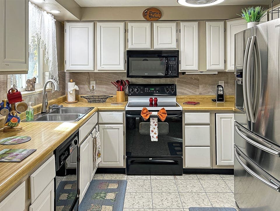 Kitchen with modern appliances, spacious counters, and cozy bar.