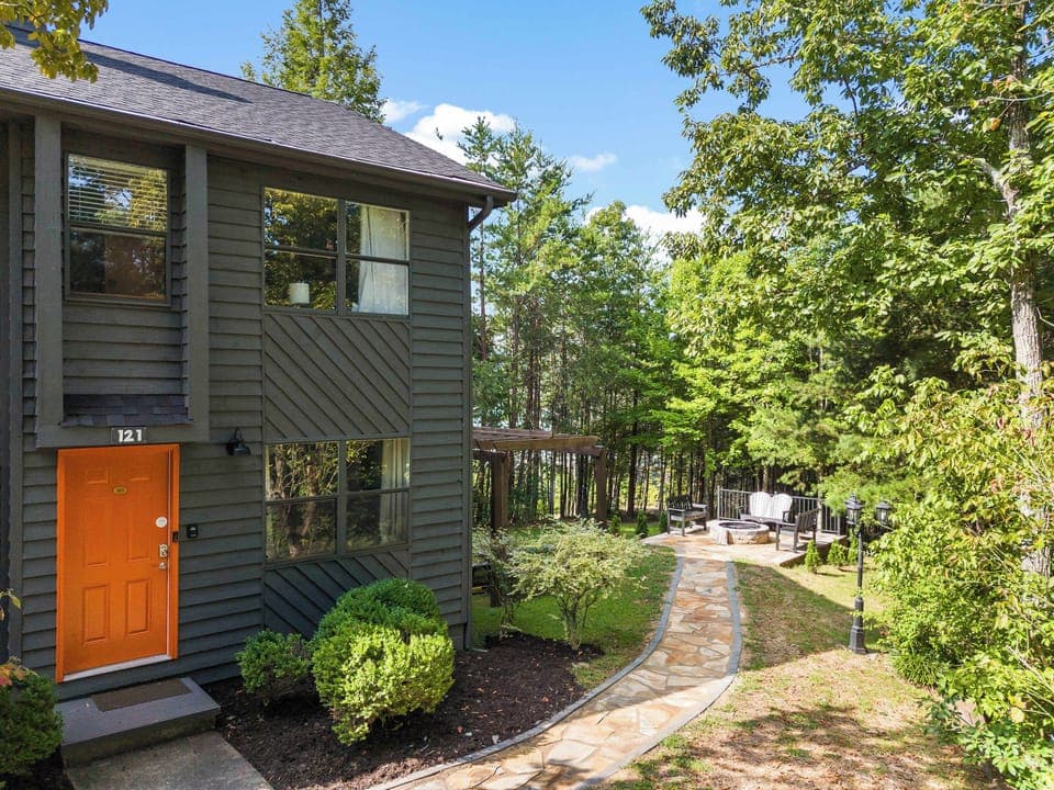 Bright orange door welcomes you to lush greenery and serene outdoor seating!