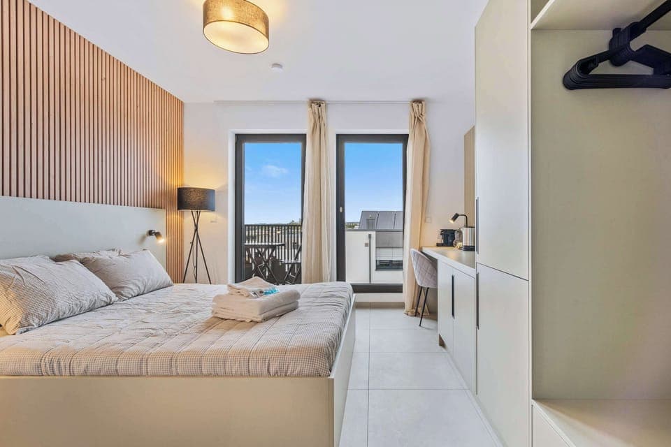 Inviting Living and Sleeping Space – Unwind in a cozy area featuring a queen-sized bed and a sophisticated wooden accent wall.