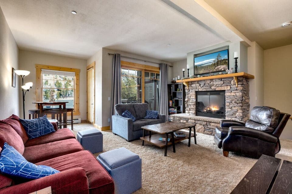 Relax by the fireplace in this cozy living room, offering a perfect space to unwind after a day of outdoor adventures. Enjoy scenic mountain views from the large windows.