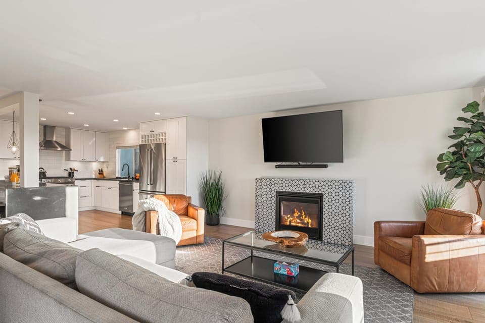 Unit 1: Bright open living room with fireplace, TV, and sofa.