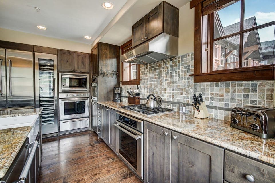 Charming kitchen with rich wood cabinetry, mosaic backsplash, and premium appliances for a true home-away-from-home feel.
