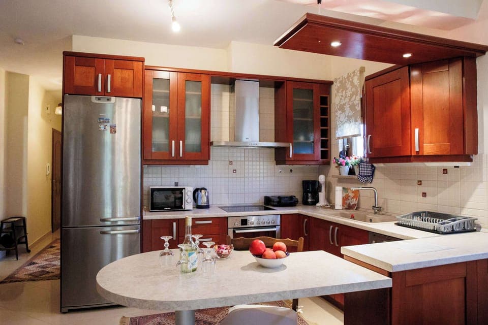 Charming, fully equipped kitchen with rich wood cabinetry and a round dining table ideal for family-style cooking and casual gatherings.