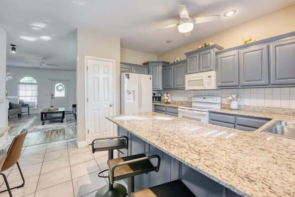 Spacious kitchen with granite countertops, light blue cabinetry, and breakfast‑bar seating—perfect for cooking and casual dining.