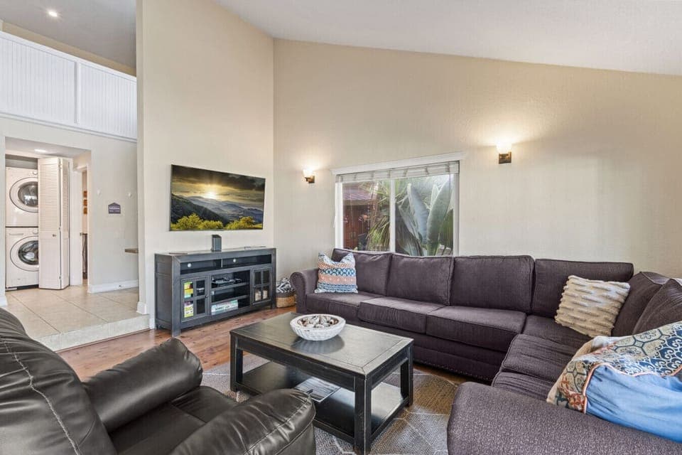 Bright living room with vaulted ceilings, plush sectional, and smart TV for relaxed evenings in.