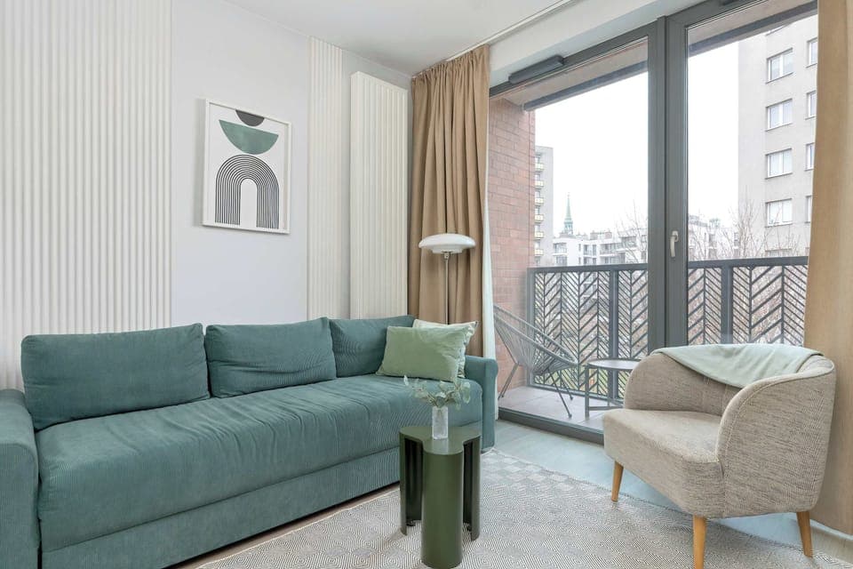 Bright living room with a fold-out corner sofa, balcony doors, and modern decor.
