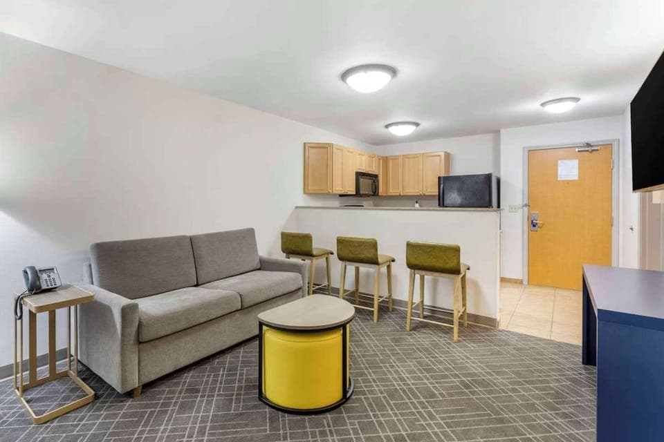 Open living space with sofa, bar stools, and kitchen right behind