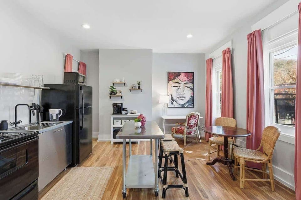 Fully equipped kitchen with dining table and coffee station, plus sunny window-side seating.