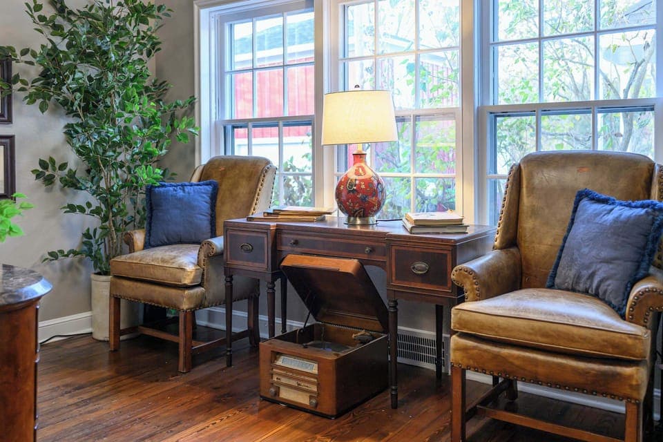 Inviting reading nook with classic leather chairs, warm lighting, and a charming desk overlooking the windows.